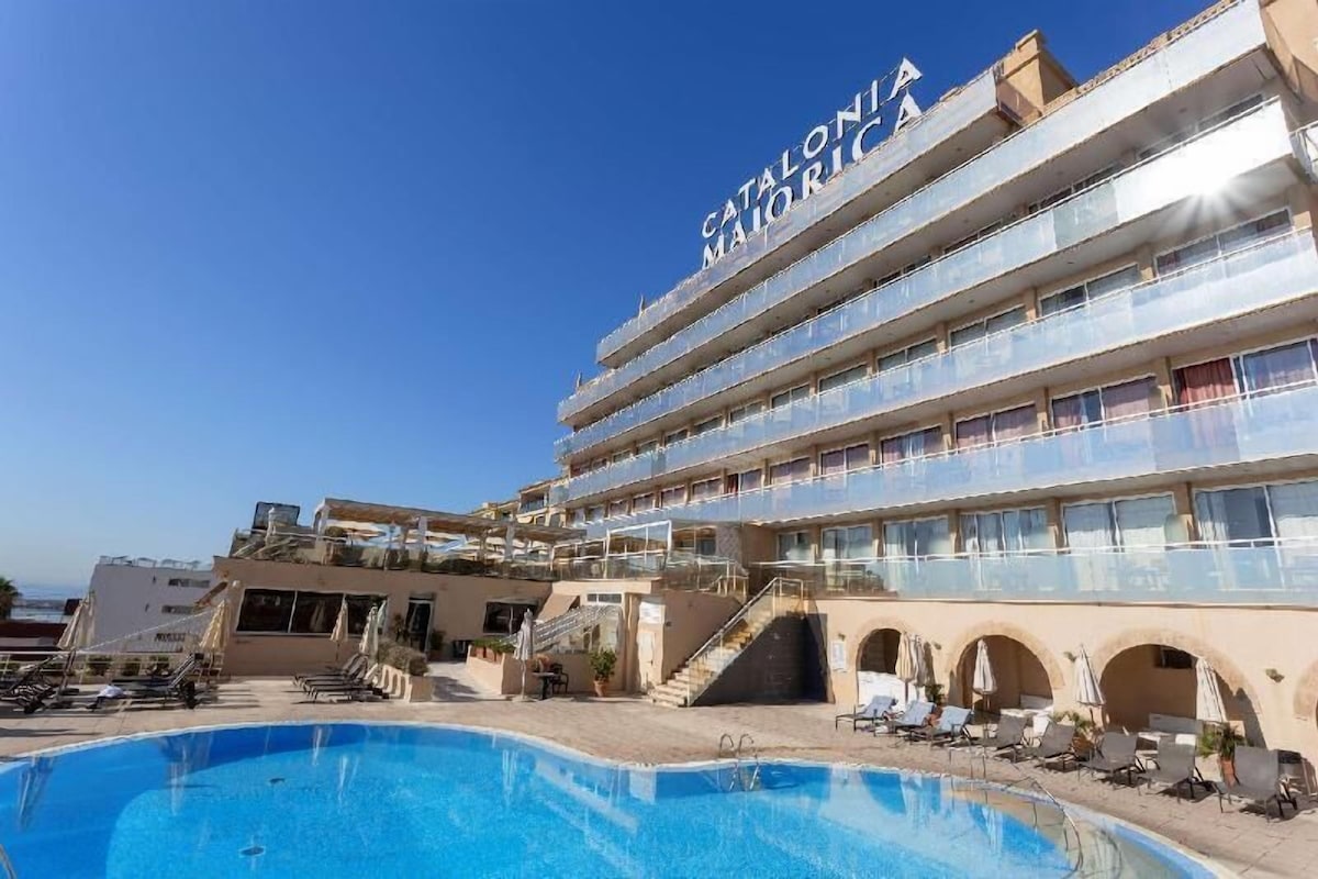 Un hotel con piscina, varios balcones y cielo despejado.