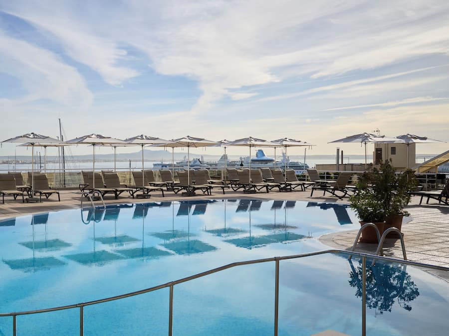 Una piscina techada, una piscina al aire libre, sombrillas