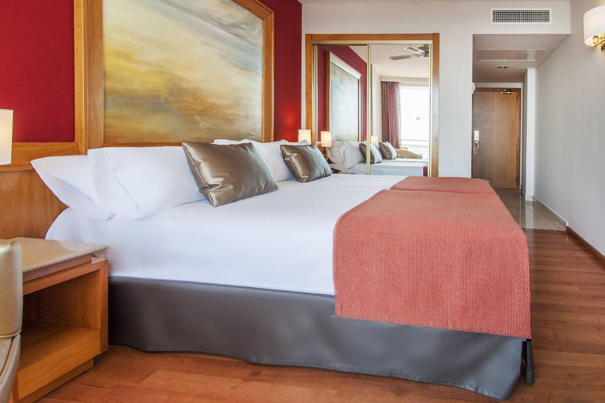 Una habitación de hotel con una cama grande, una mesita de noche, una lámpara y un cuadro en la pared.