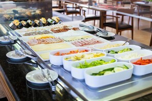 Un bufé con diversas opciones de comida, incluyendo carnes, quesos y verduras.