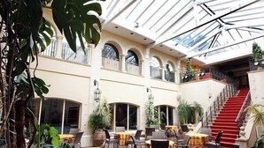 A multi-level indoor space with tables and chairs, a staircase, and large windows. - Nailcote Hall Hotel (Solihull)