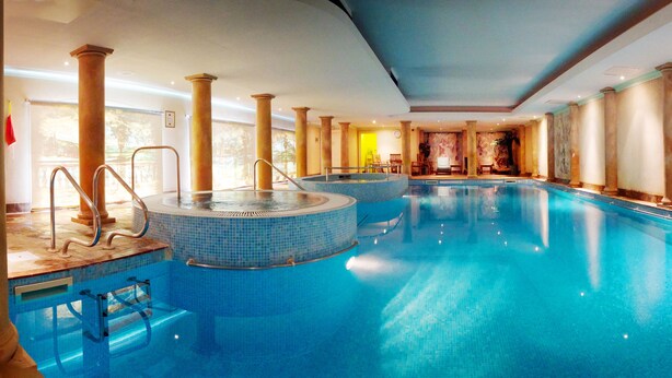 A large indoor swimming pool with multiple hot tubs and a sunlit room in the background. - Nailcote Hall Hotel (Solihull)