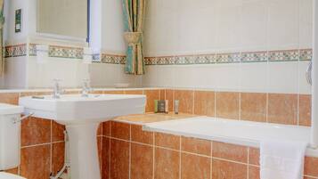 A bathroom with a pedestal sink, a toilet, and a bathtub.