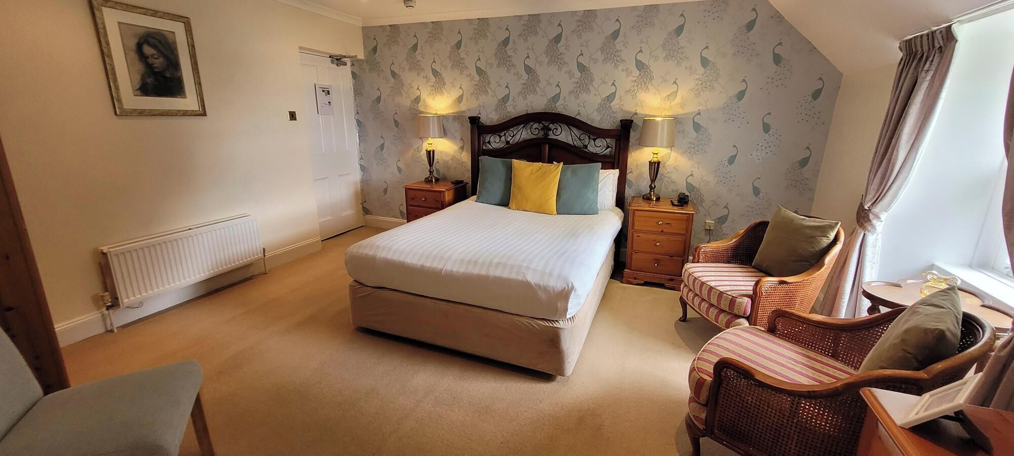 A bedroom with a large bed, two bedside tables with lamps, a chair, a dresser, and a radiator.