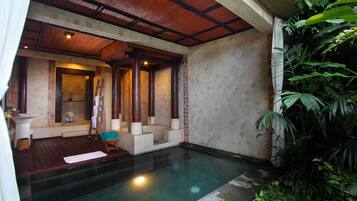 Un área de spa con piscina, terraza de madera y vistas a exuberante vegetación.