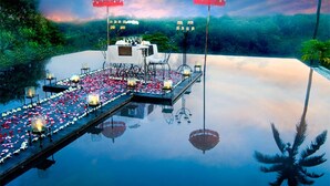 Ein Infinity-Pool mit einer schwimmenden Bar, roten Sonnenschirmen und Kerzen.