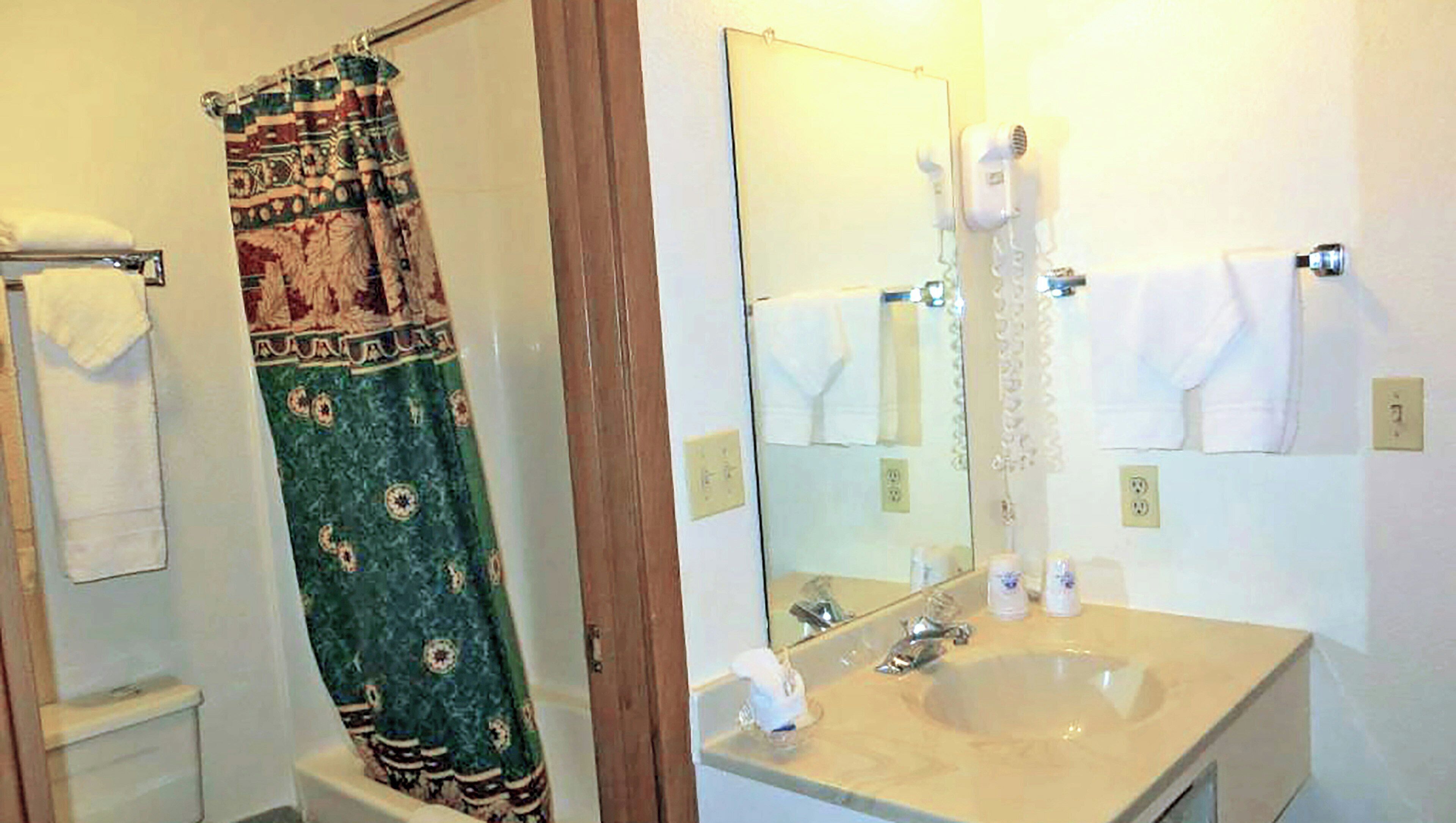 A bathroom with a shower curtain, a sink, a mirror, and towels.