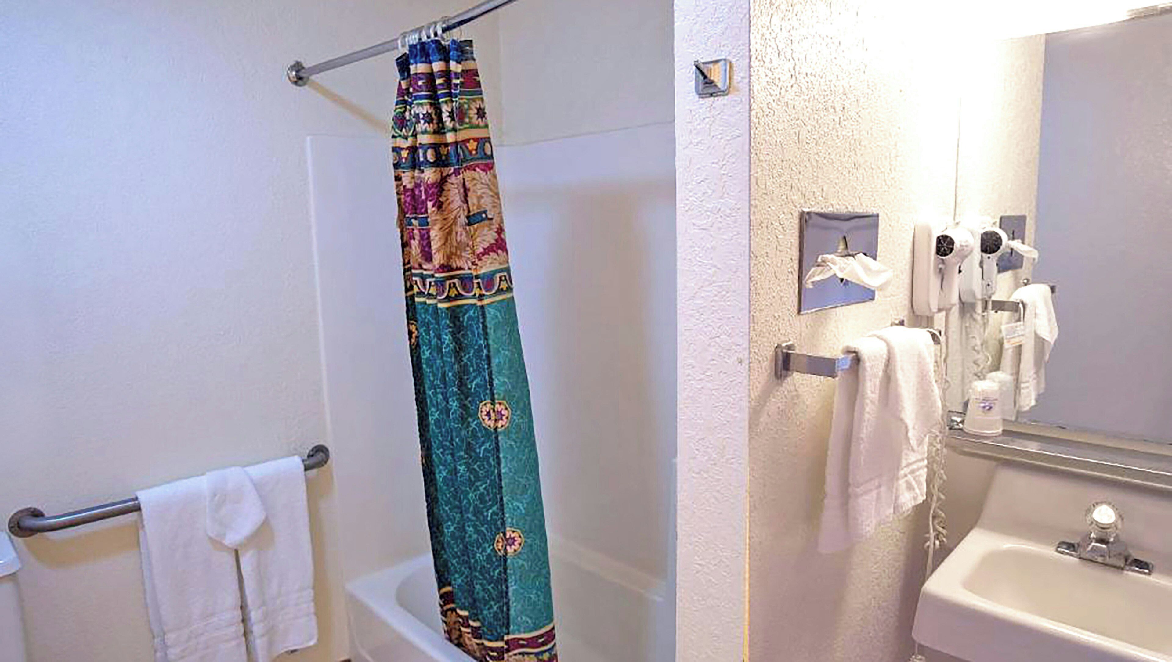 Un baño con cortina de ducha, toallero, lavabo y espejo.