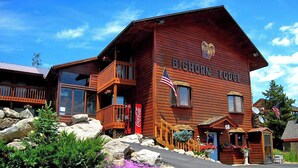 A two-story log cabin with a balcony, a Coca-Cola sign, and an American flag. - Big Horn Lodge (Grand Lake)