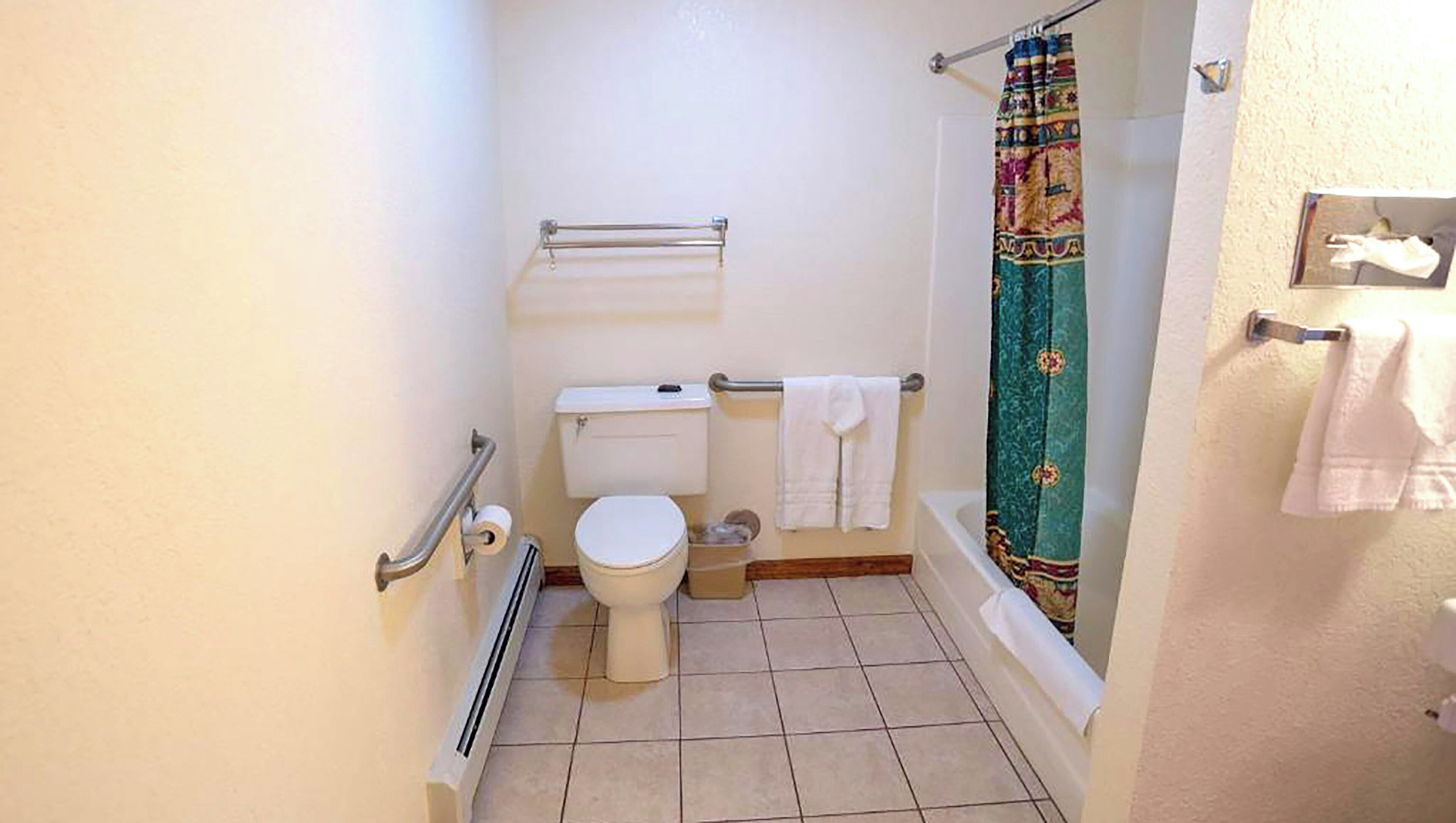 A small bathroom with a toilet, a shower curtain, and a towel rack.
