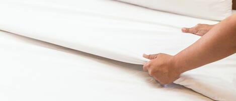 A hand adjusting a mattress on a bed.
