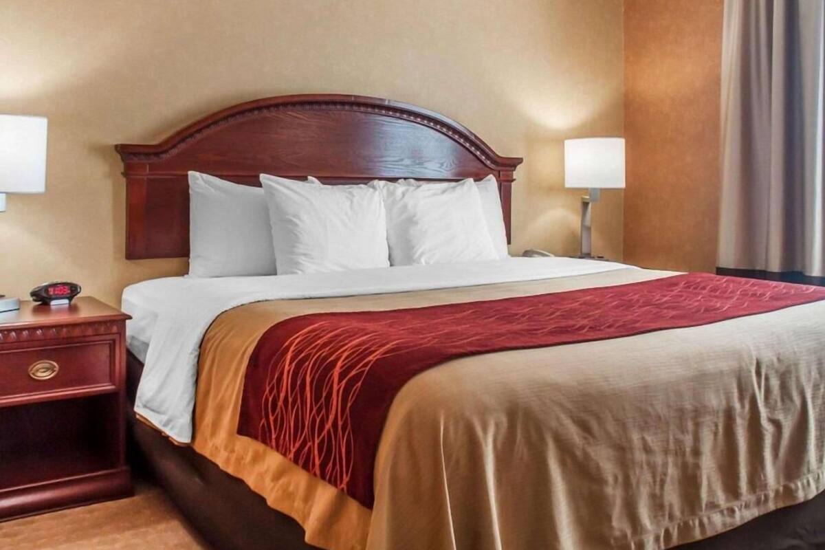 A hotel room with a large bed, wooden headboard, two bedside tables, and a nightstand.