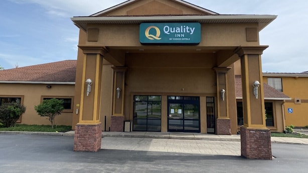 A Quality Inn by Choice Hotels building with a brown facade, large entrance doors, and a clear sky.