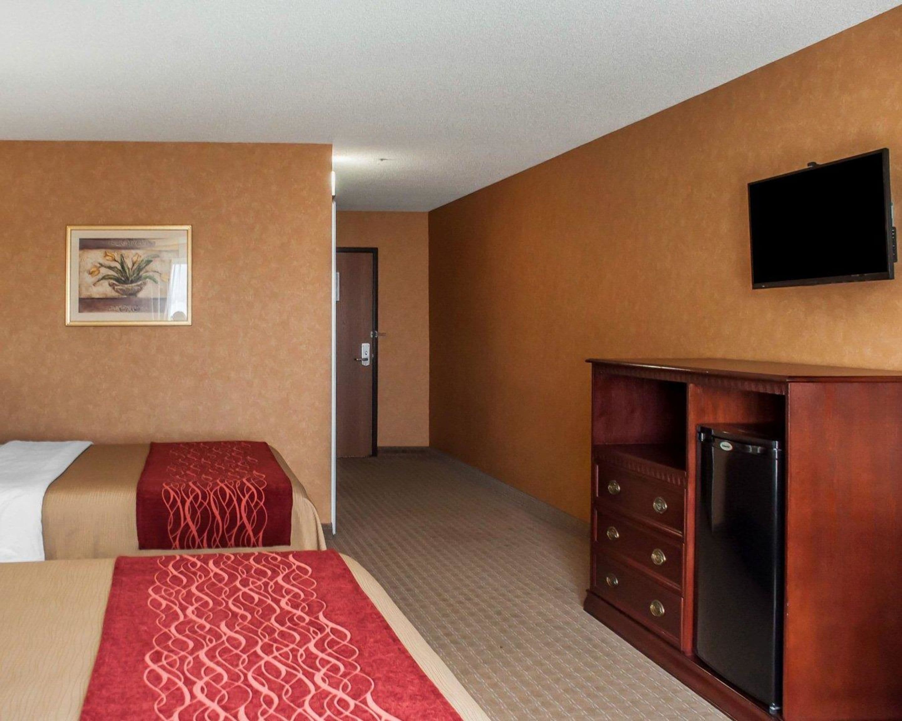 Ein Hotelzimmer mit einem Bett, einem Schminktisch, einem Fernseher und einer Tür zu einem anderen Raum.