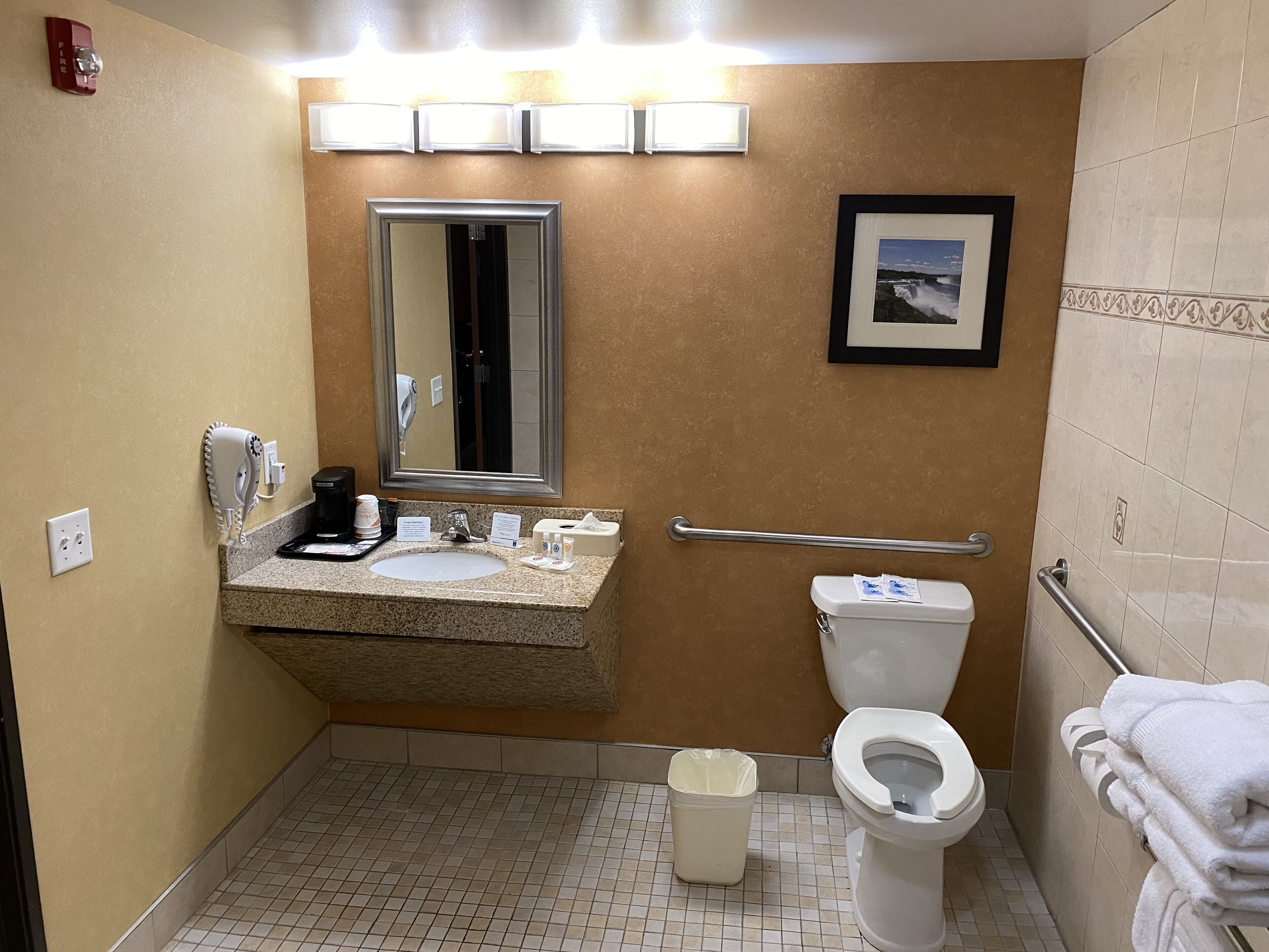 A bathroom with a sink, mirror, toilet, and hand dryer.