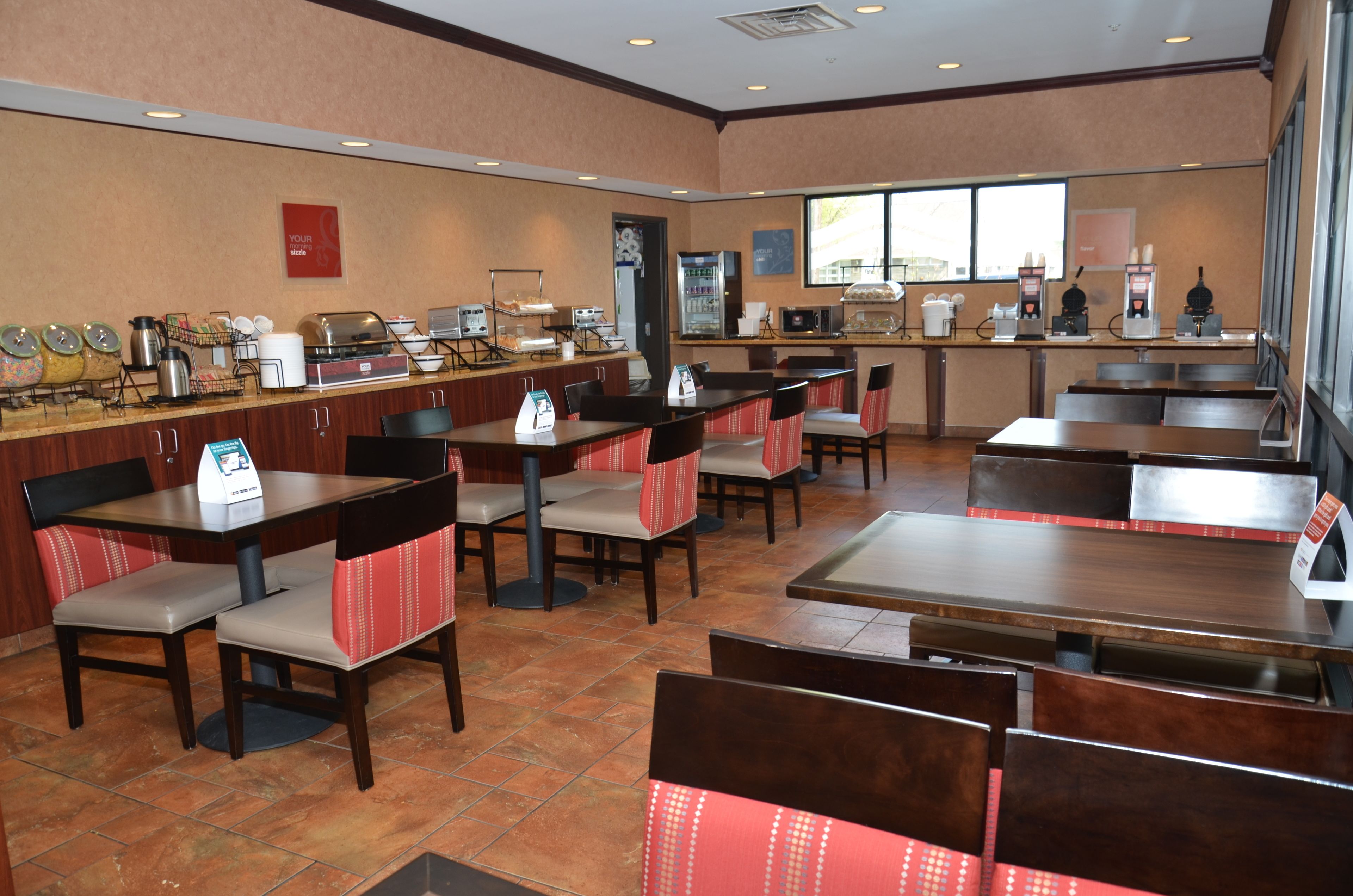 A restaurant with multiple tables and booths, equipped with coffee machines and a buffet area.