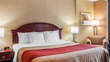 A hotel room with a large bed, two bedside tables, a chair, and a painting on the wall.