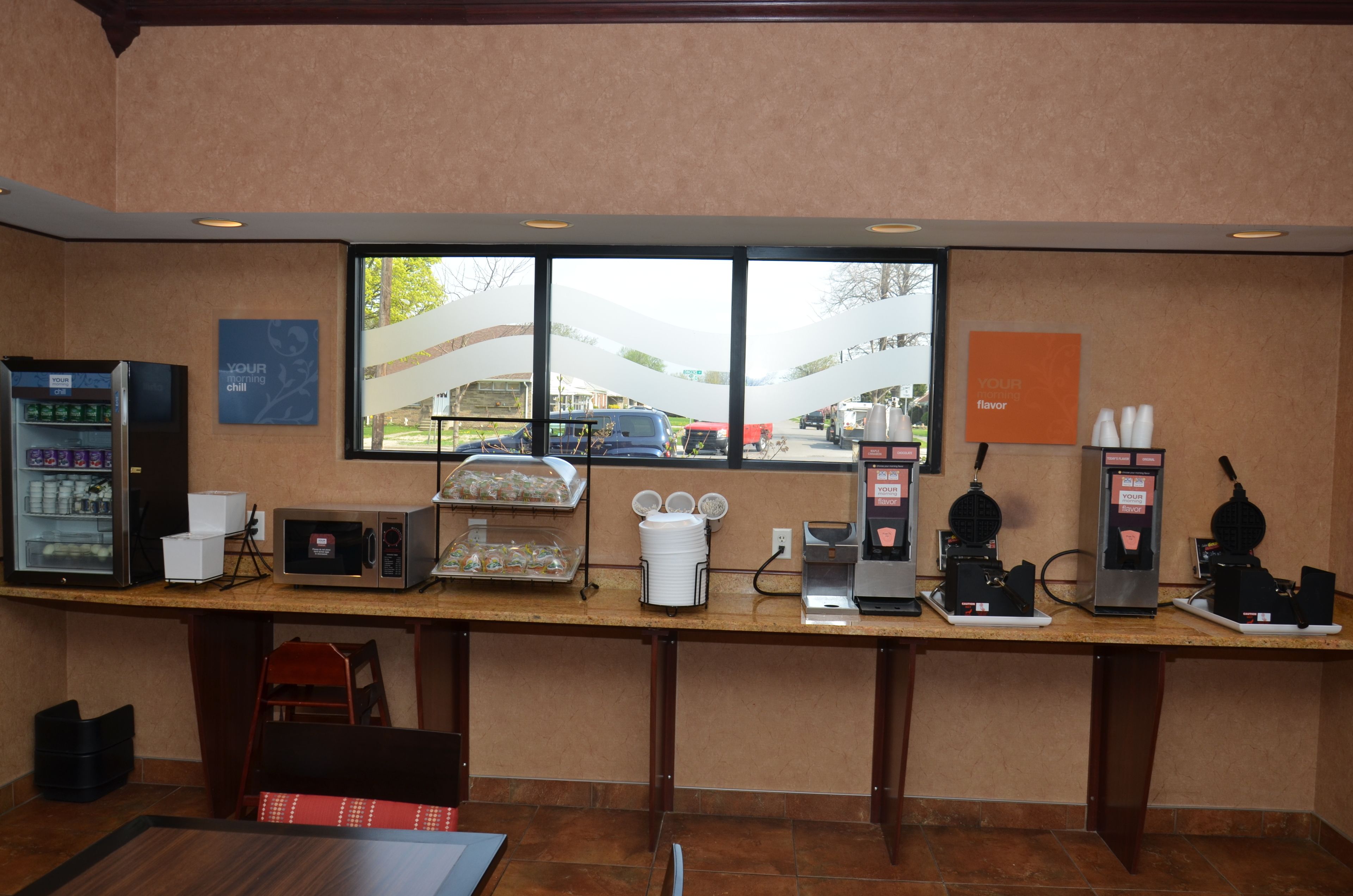 A coffee station with a vending machine, a microwave, and a waffle maker.