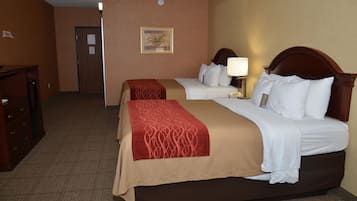 A hotel room with two beds, a desk, and a door.