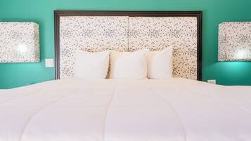 A bed with white bedding, a headboard with a speckled pattern, and two wall-mounted lamps.