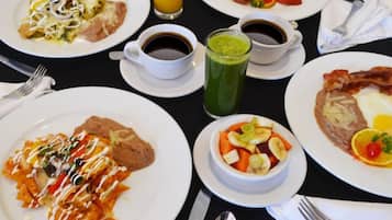 A breakfast setting with plates of food, coffee, and a green drink.