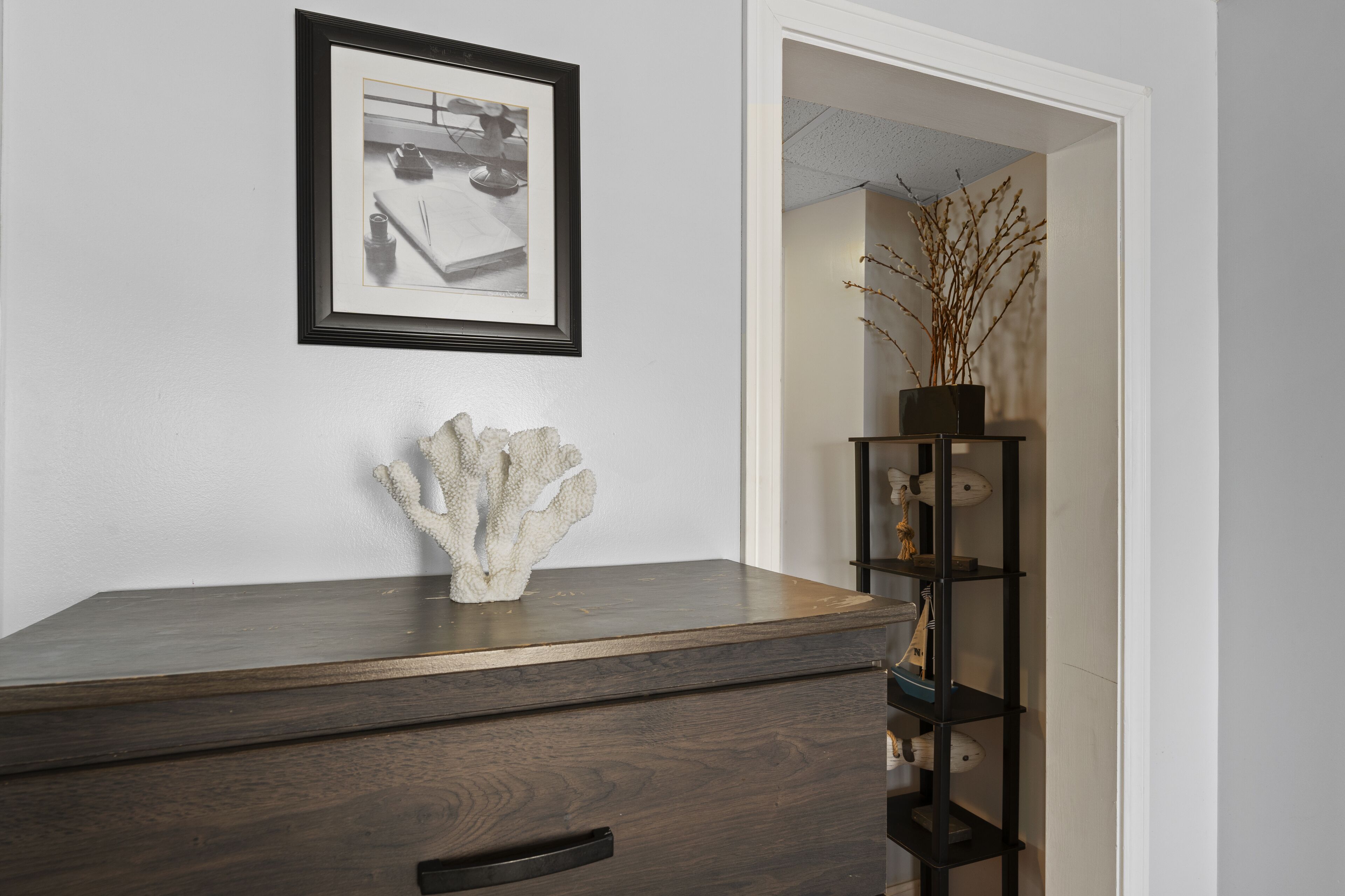 A dark wooden dresser with a framed picture and a decorative coral piece on top.