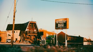 A building with a sign for the Wrangell Hotel, featuring a large outdoor deck and a truck parked in front. - Wrangler Inn  (Mobridge)