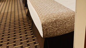 A hotel room with two beds, a large window with curtains, a view of the pool, and a small table with a lamp. - Wrangler Inn  (Mobridge)