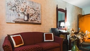 A cozy room with a red sofa, a wooden coffee table, and a vase of flowers. - Wrangler Inn  (Mobridge)