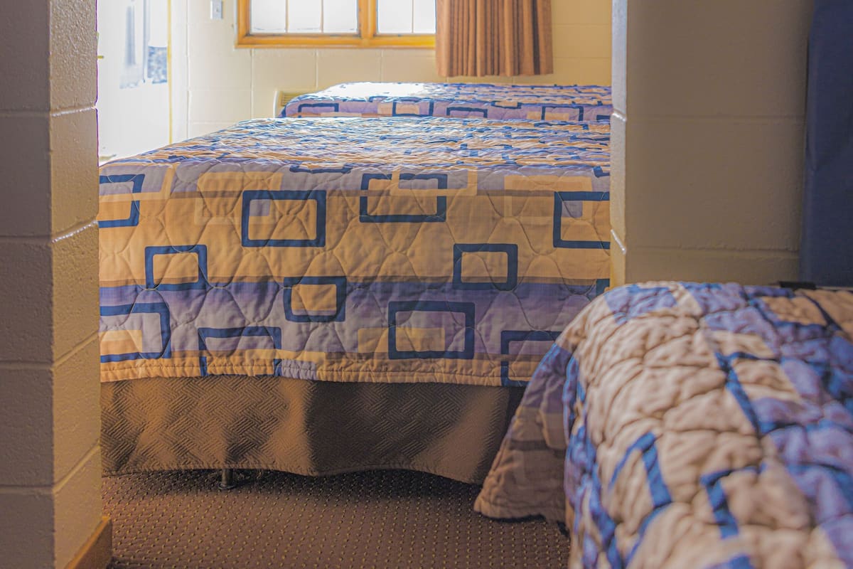 A room with a bed, a window with curtains, and a door.