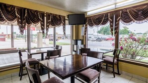 Un restaurante con un amplio ventanal, un televisor de pantalla plana y una mesa con sillas.