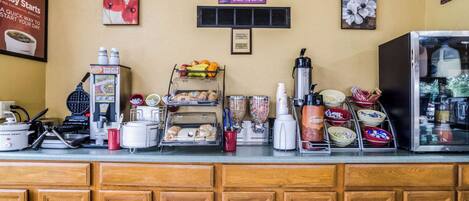 A kitchen counter with various appliances and food items, including a coffee maker, toaster, and a fruit basket.