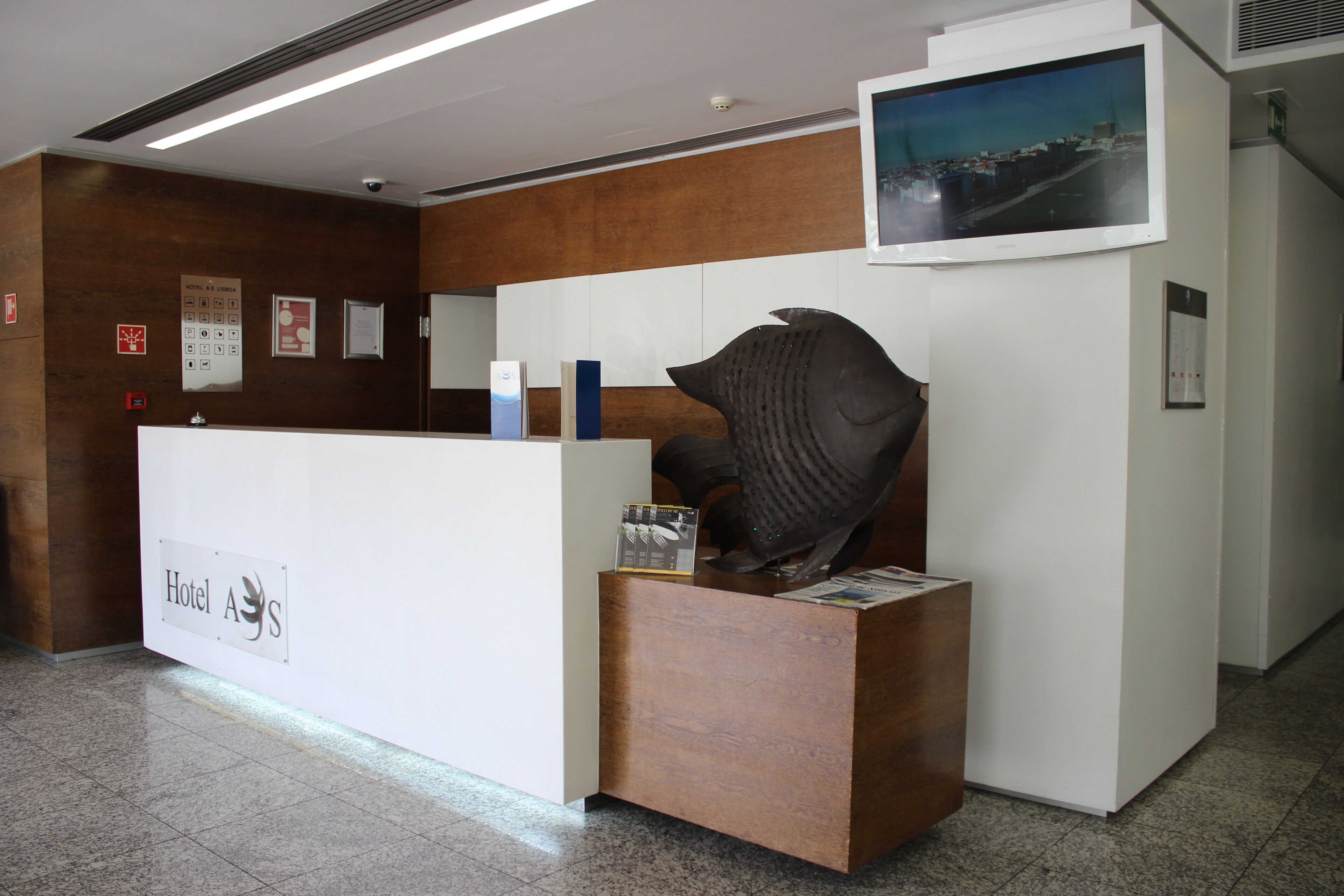 Una recepción con diseño moderno, un televisor montado y una gran escultura abstracta.