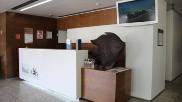 Una recepción con diseño moderno, un televisor montado y una gran escultura abstracta.