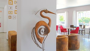 Un interior moderno con una escultura de madera única, sillas rojas y un comedor con mesas.