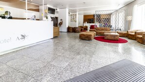Un hall de hotel con mostrador de recepción, zona de estar y bar.