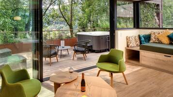 Een modern buitenverblijf met rieten stoelen, een houten tafel en een jacuzzi.