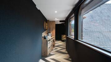 Un pasillo con piso de diseño espiga, un armario de madera con un teléfono, y una ventana con vista a un tejado con tejas.