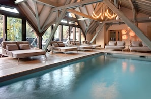 Zona de piscina con sillones de descanso y vistas al exterior.