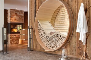 Un cuarto de spa con pared de piedra, un banco de madera y un espejo grande que refleja el ambiente.