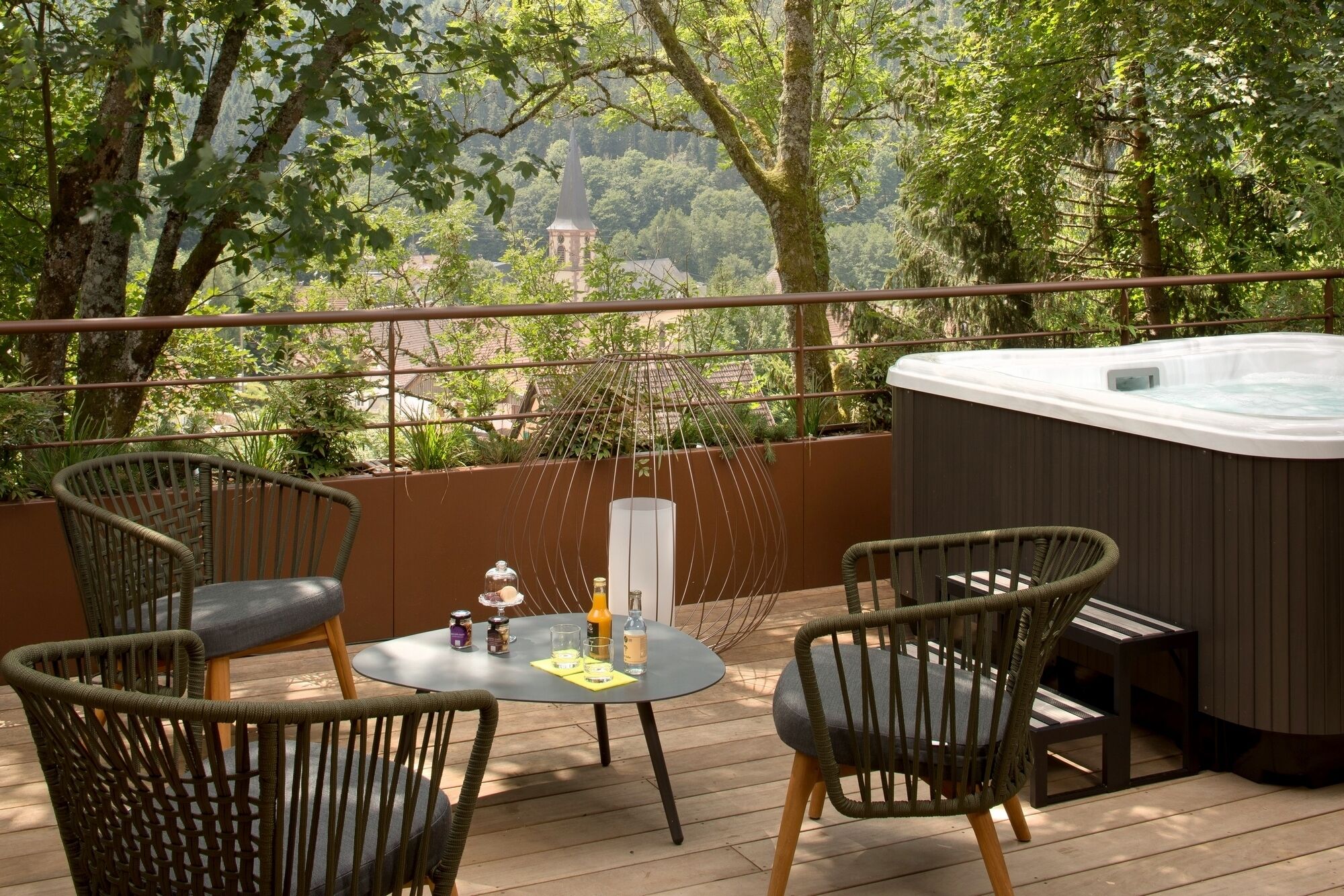Una terraza con sillas de mimbre, una mesa redonda y un jacuzzi.