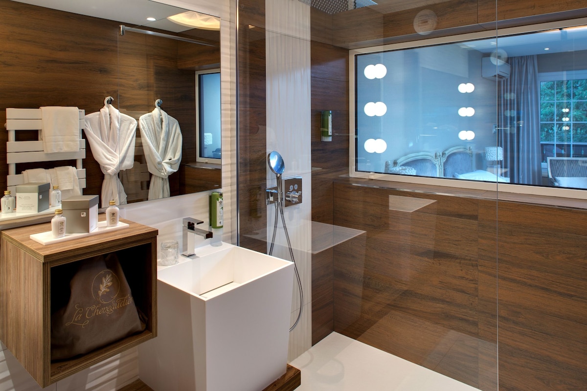 A modern bathroom with a large mirror, vanity, and a shower area.
