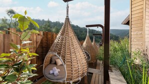 A wooden deck with hanging wicker chairs and a view of a forested area. - La Cheneaudiere - Hôtel Spa - Relais & Châteaux (Colroy-la-Roche)