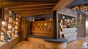Un intérieur en bois avec un comptoir d’accueil, des étagères remplies d’objets et un mur orné de motifs.
