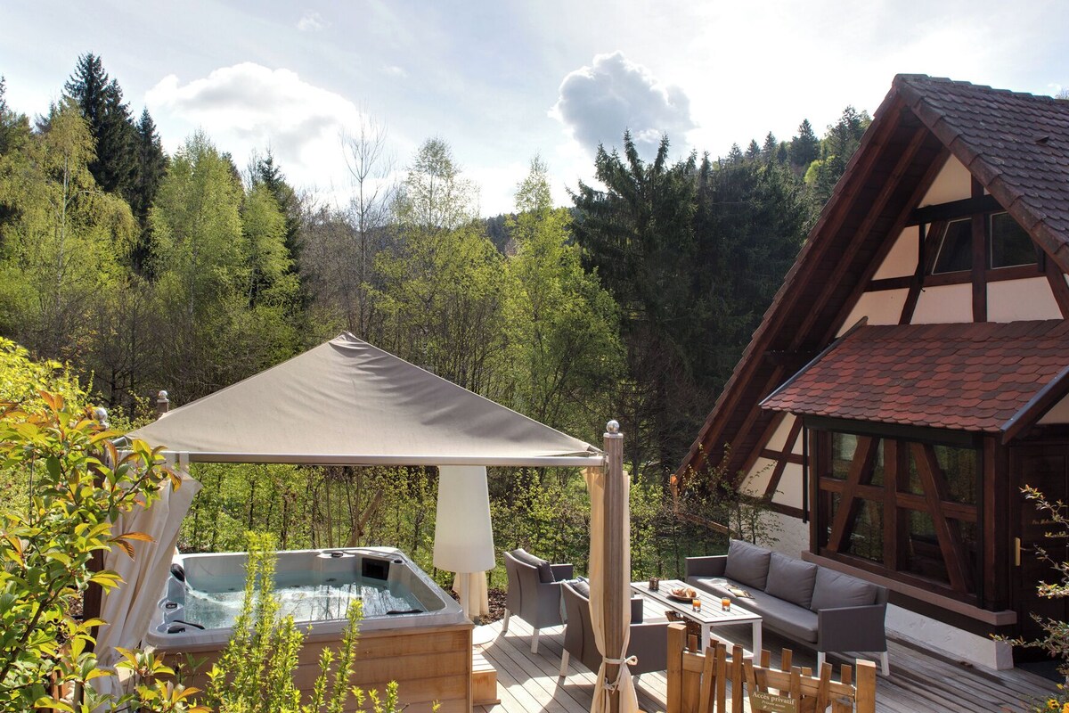 Un jacuzzi, asientos exteriores y una cabaña de madera en un bosque.
