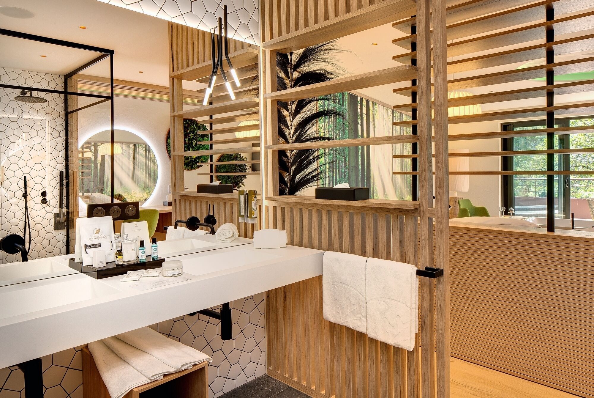 A modern bathroom with a white vanity, wooden paneling, a large mirror, and a view of greenery outside.