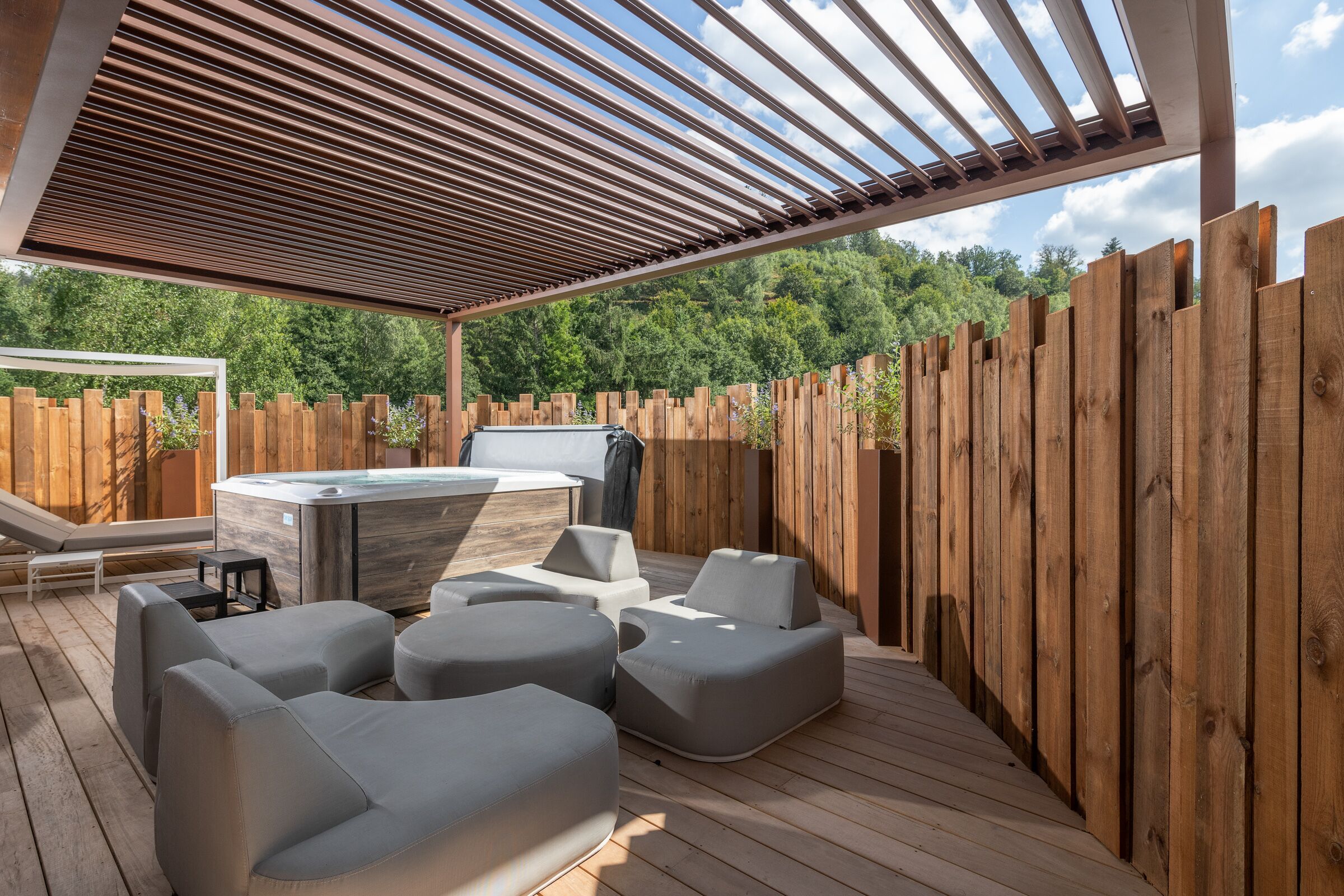 An outdoor patio with wooden deck, a hot tub, and modern seating.