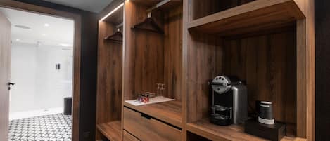 A modern bathroom with wooden cabinetry, a coffee machine, and a glass shower enclosure.