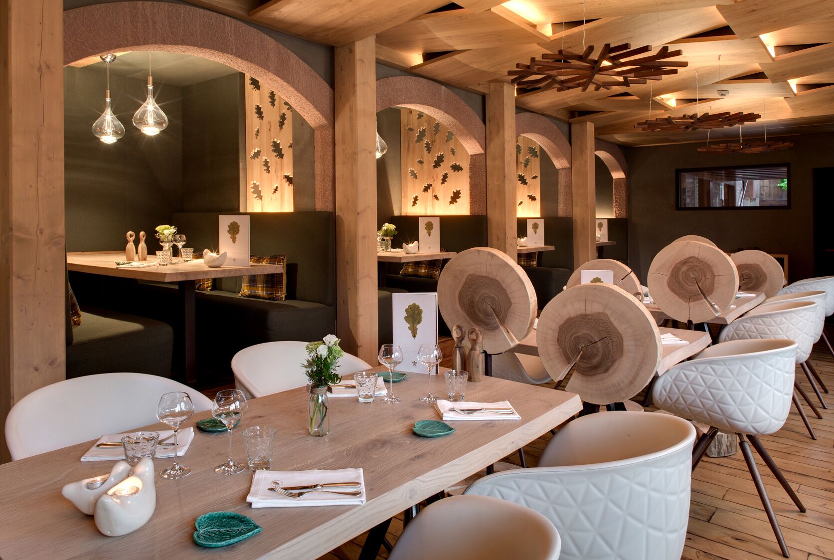 A restaurant with wooden tables, white chairs, and a warm, wooden interior.