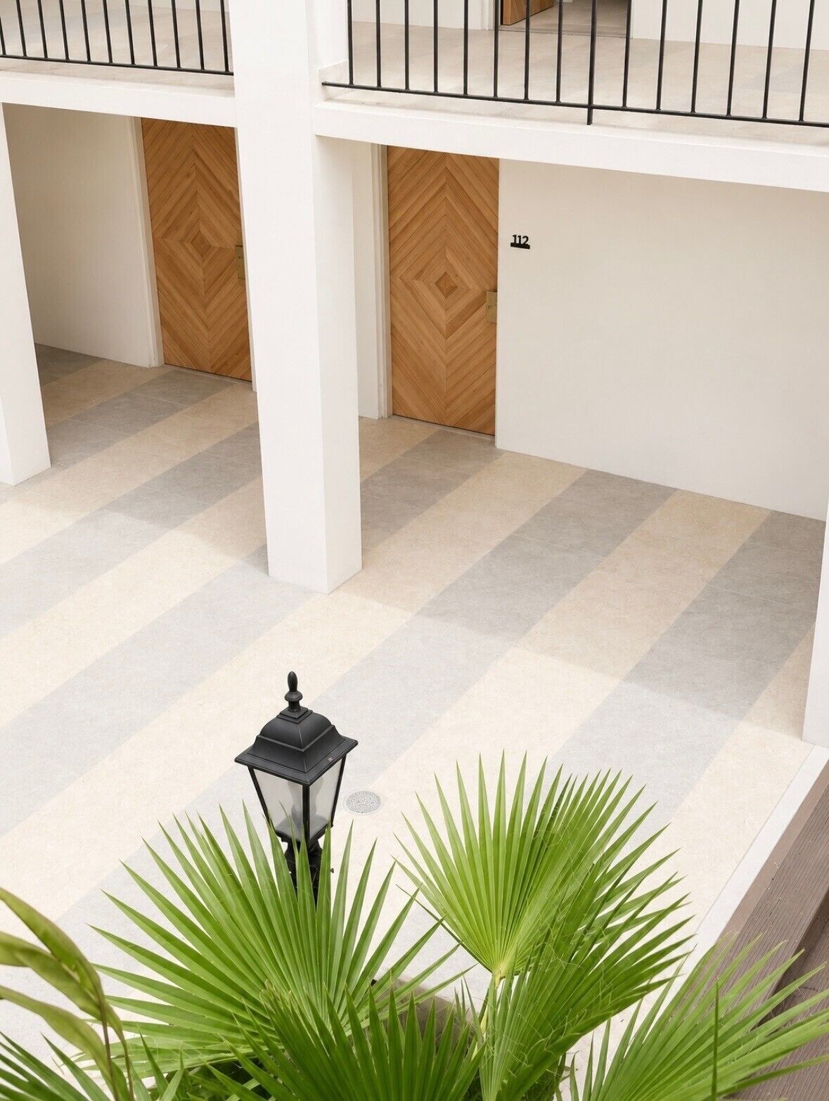 A multi-level interior with a checkered floor pattern, a wooden door with a herringbone design, and a number '112' on the wall.